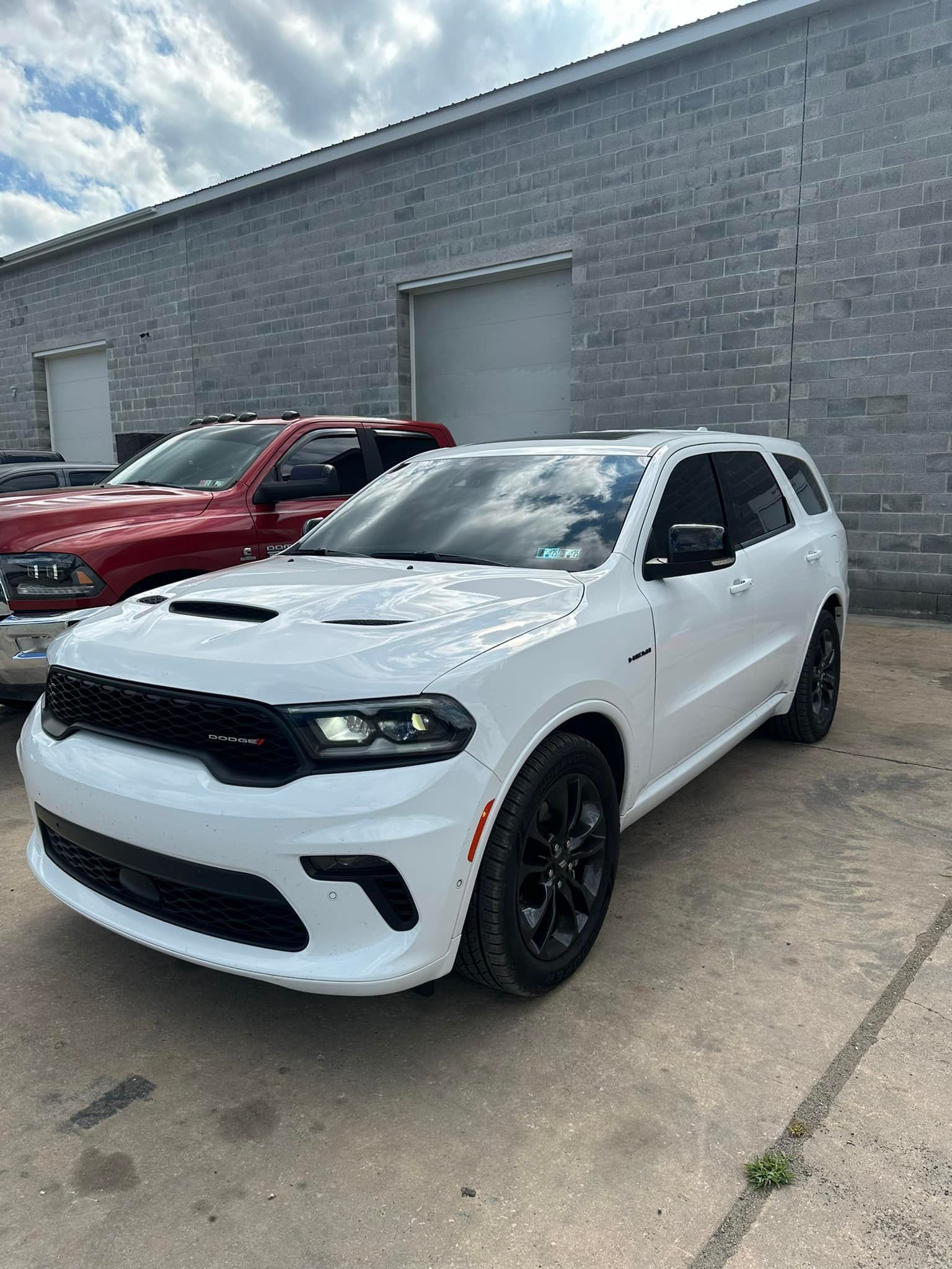 A white dodge durango is parked in front of a brick building.