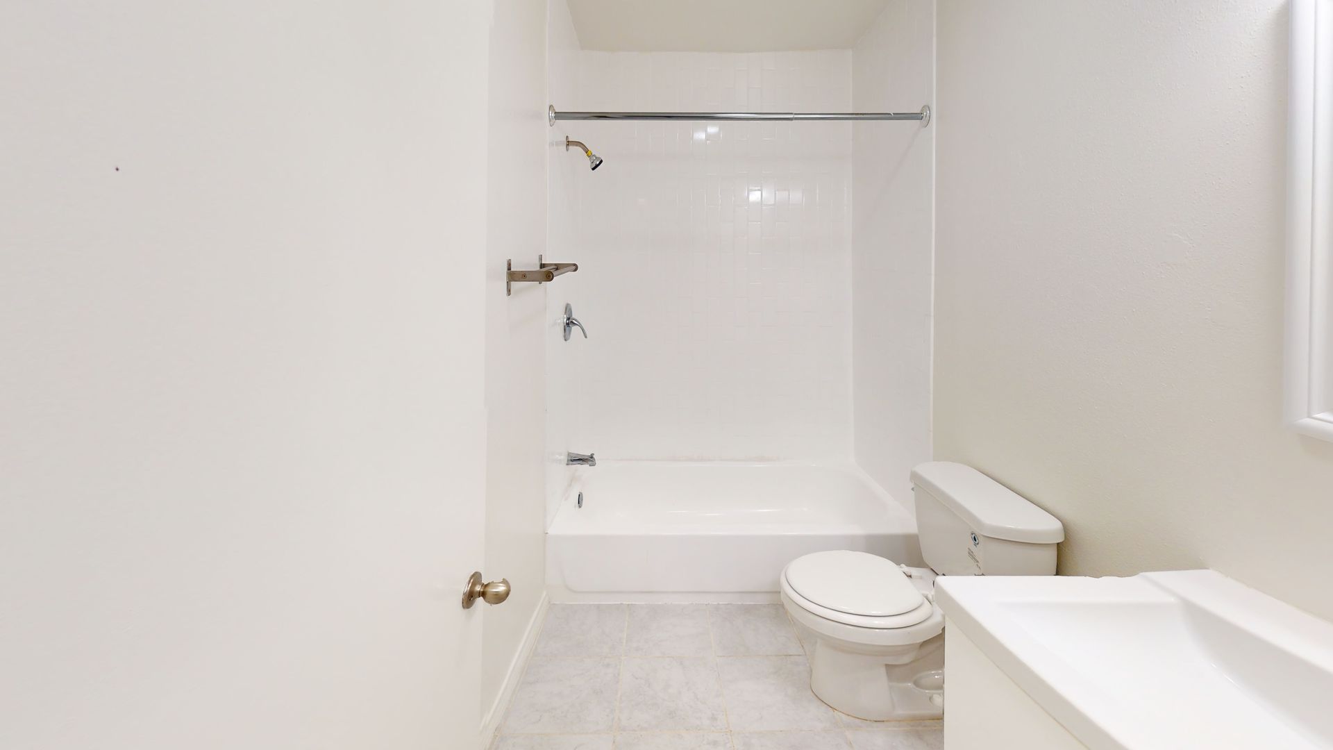 White bathroom with a shower/tub, toilet, and sink.