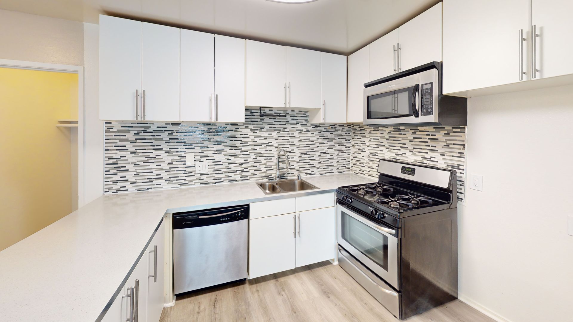 Modern kitchen with white cabinets, stainless steel appliances, and a tiled backsplash.