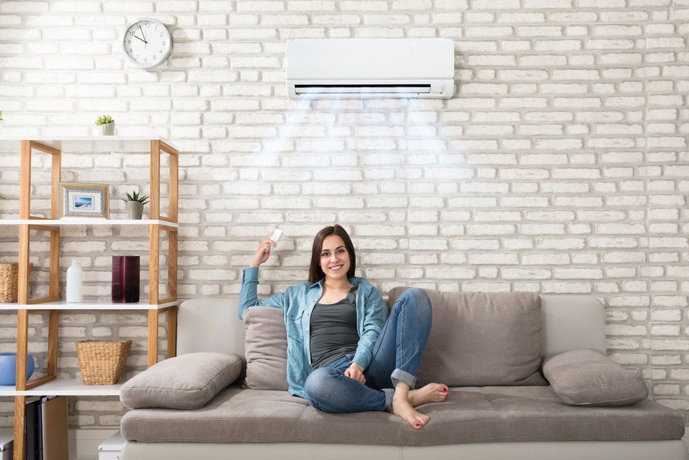 Woman Turning On Air Con — Air Conditioning Newcastle, New South Wales