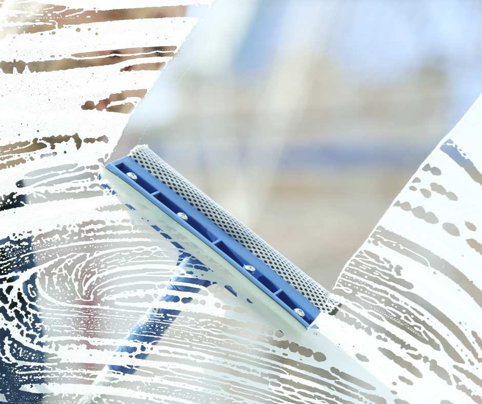 A person wearing orange gloves is cleaning a gutter on a roof