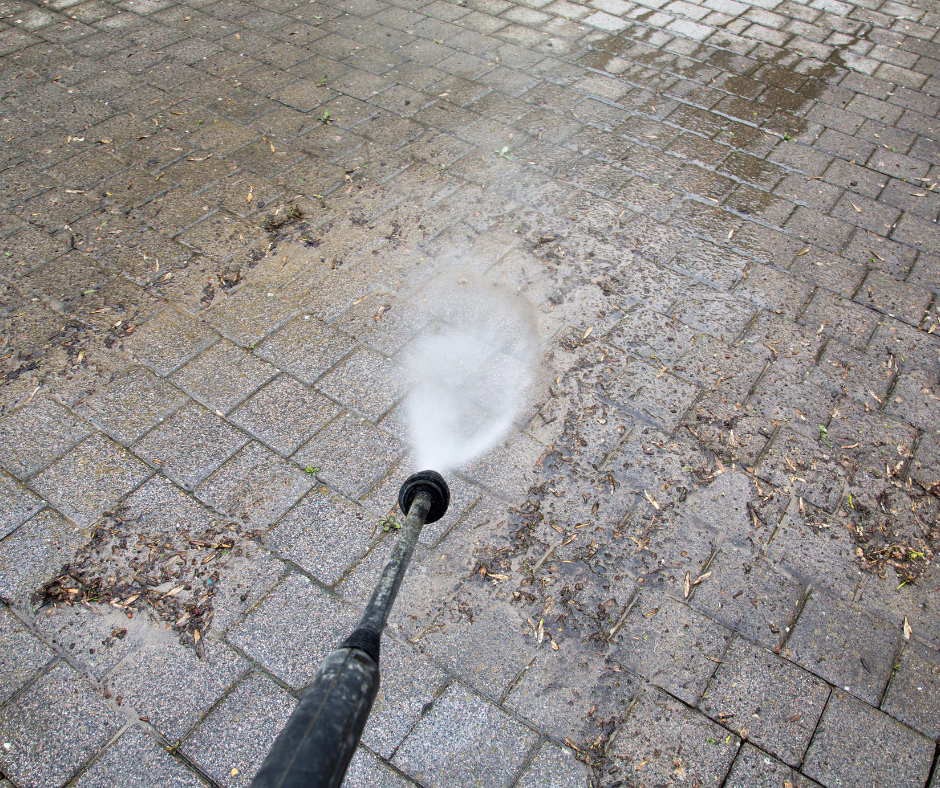 A person is cleaning the side of a house with a high pressure washer