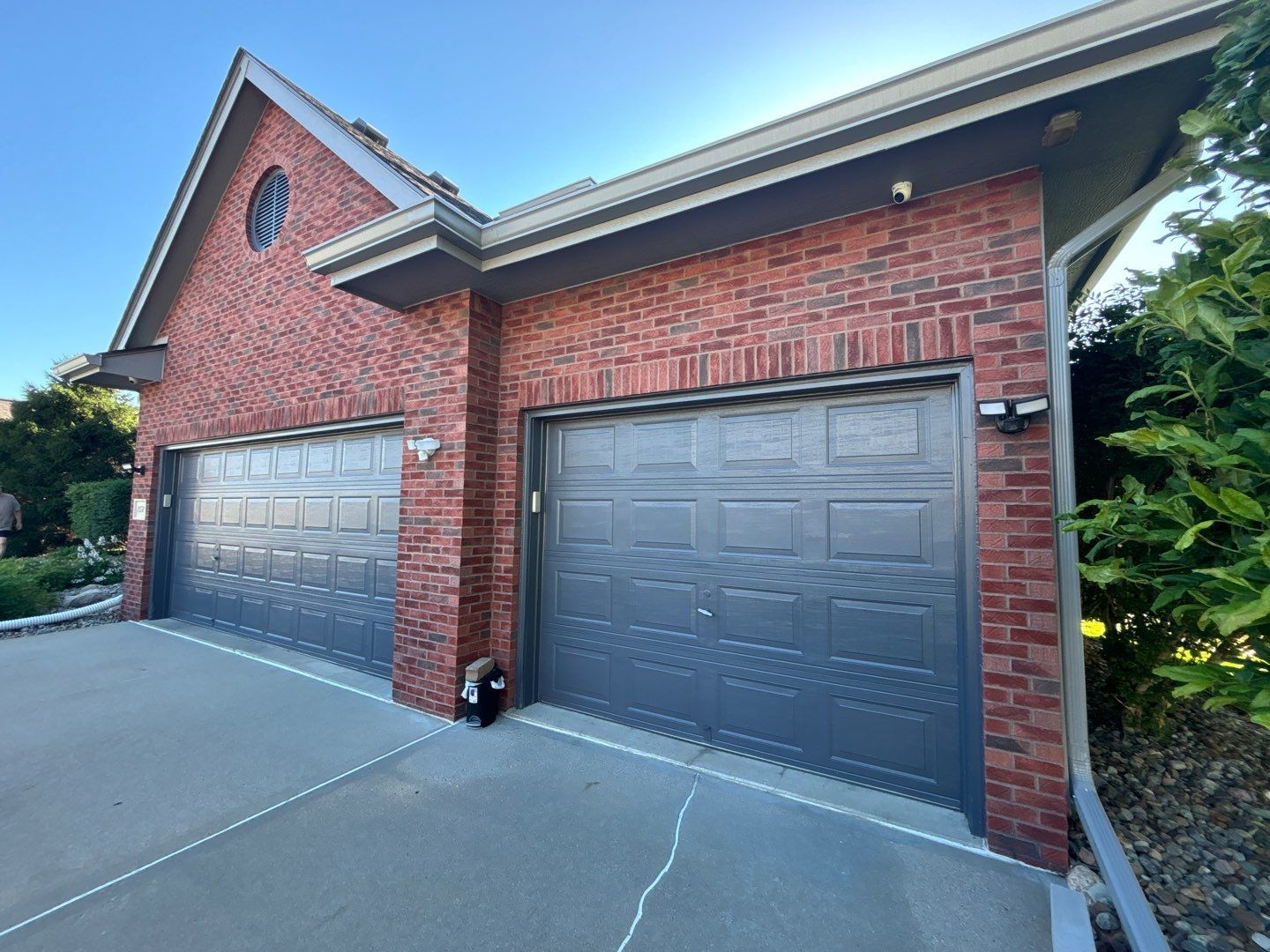 A brick house with two garage doors and a driveway.