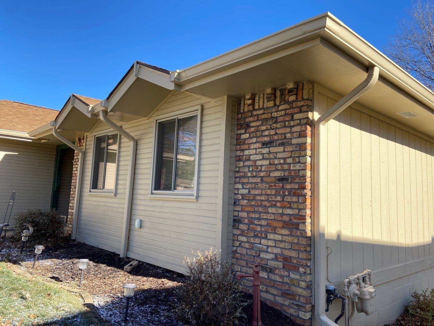 A white house with a brick wall and a gutter on the side of it.