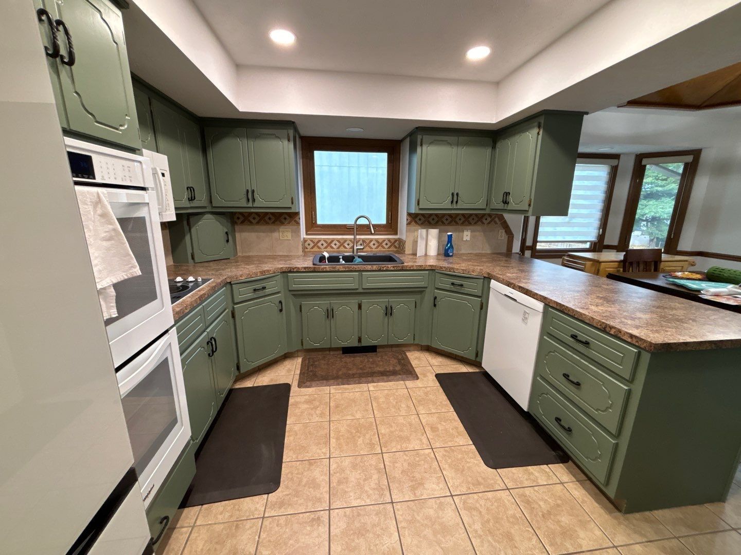 A kitchen with green cabinets and granite counter tops.