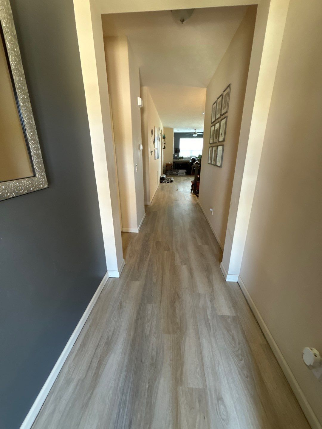 A hallway with a wooden floor and a mirror on the wall.
