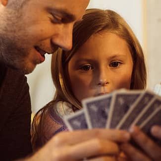 Man and child looking at playing cards, close-up.