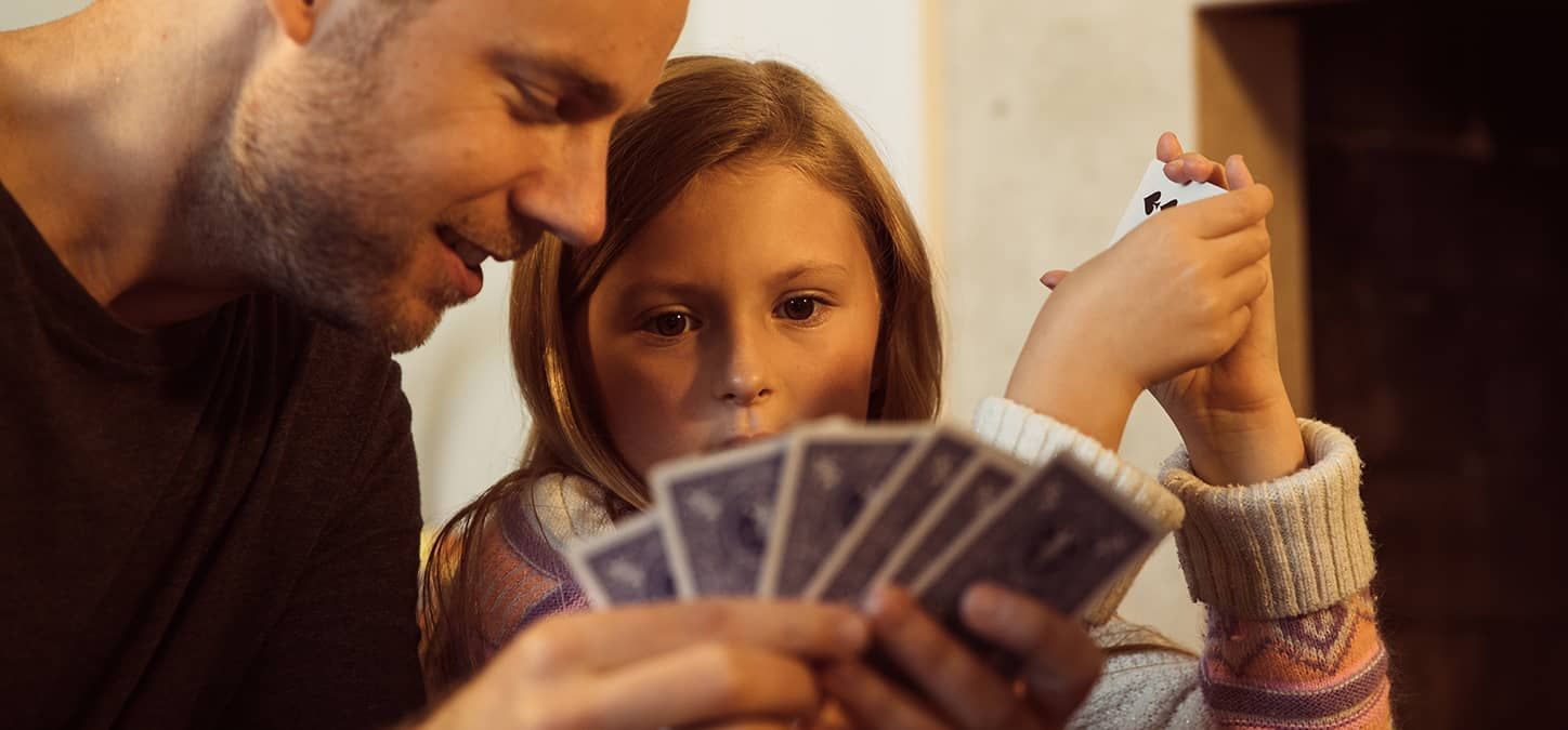 A man and a little girl are playing a game of cards.