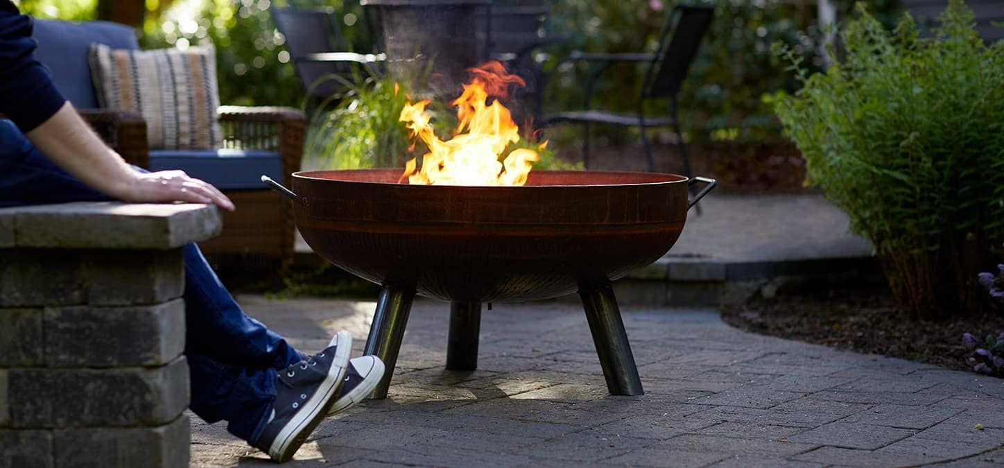 sneakers near a fire pit with flames, in an outdoor patio setting.