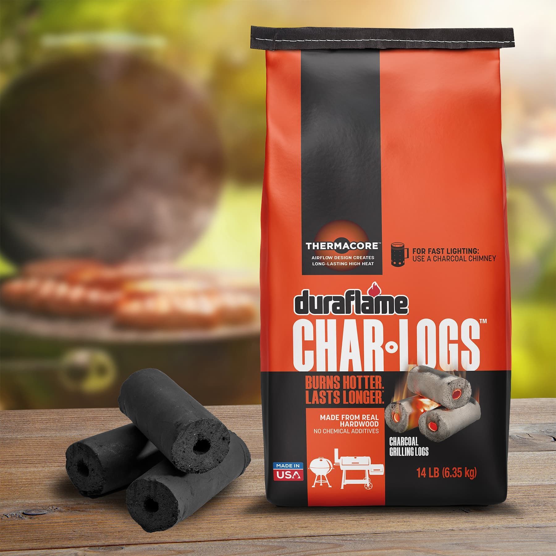 Bag of duraflame Char-Logs quick lighting charcoal, with grill and sausages blurred in background. Char-Logs High heat charcoal logs are stacked next to bag