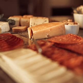 A close up of charcuterie and cheese board  with a fireplace in the background