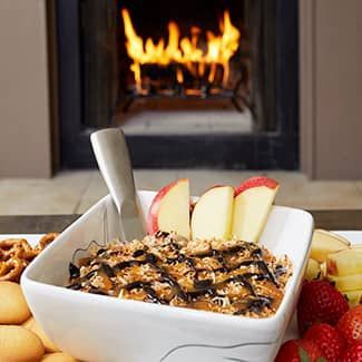 cookie dip with fruit and cookies in front of a fireplace.