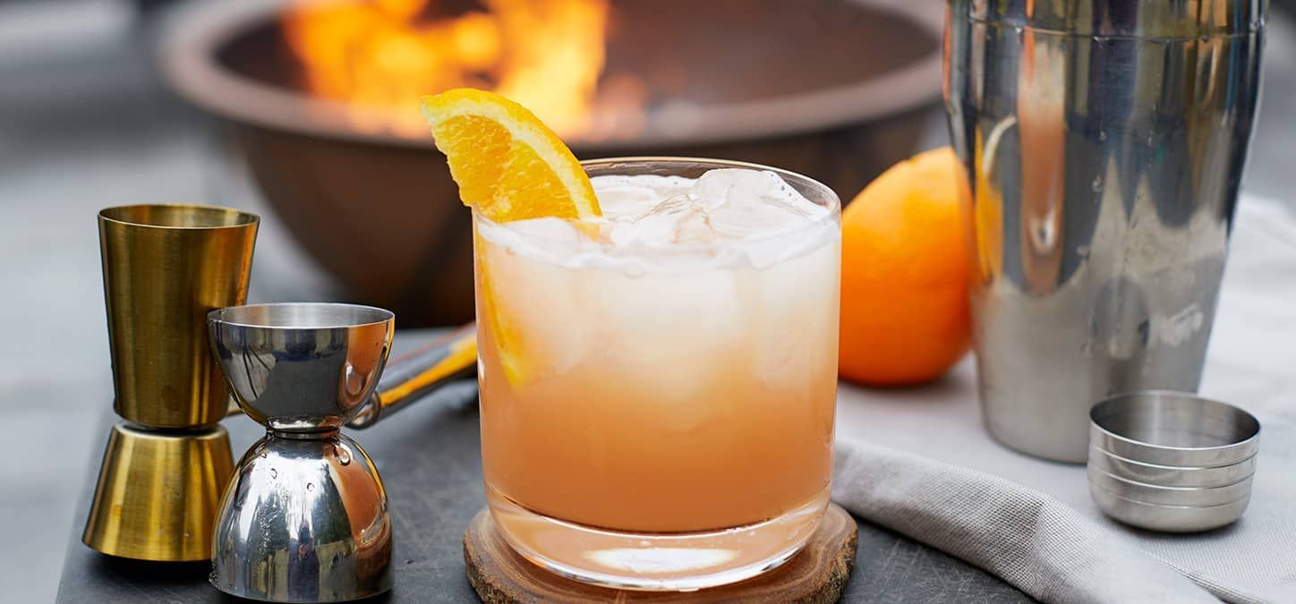 There is a fire pit in the background and an elderflower greyhound cocktail in the foreground.