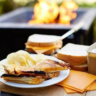 A grilled cheese sandwich with potato chips on a plate on a table.