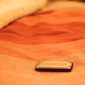 Harmonica on a textured orange surface, possibly fabric