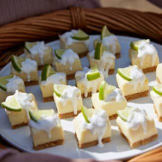 A white plate topped with  key limes bites garnished with whip cream and lime slices