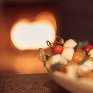 a plate of mozzarella and tomato sticks is sitting on a table in front of a fireplace.