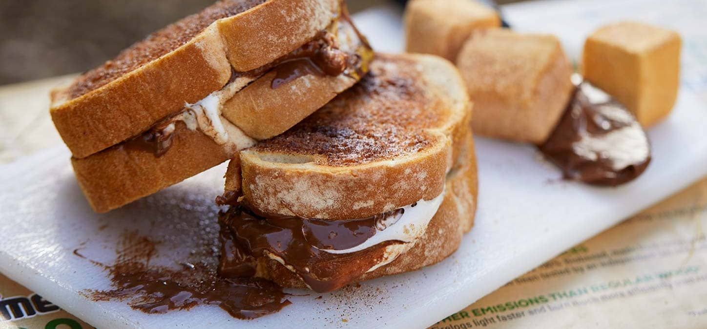 A toasted cinnamon s'moreswich with chocolate and marshmallows on a cutting board.