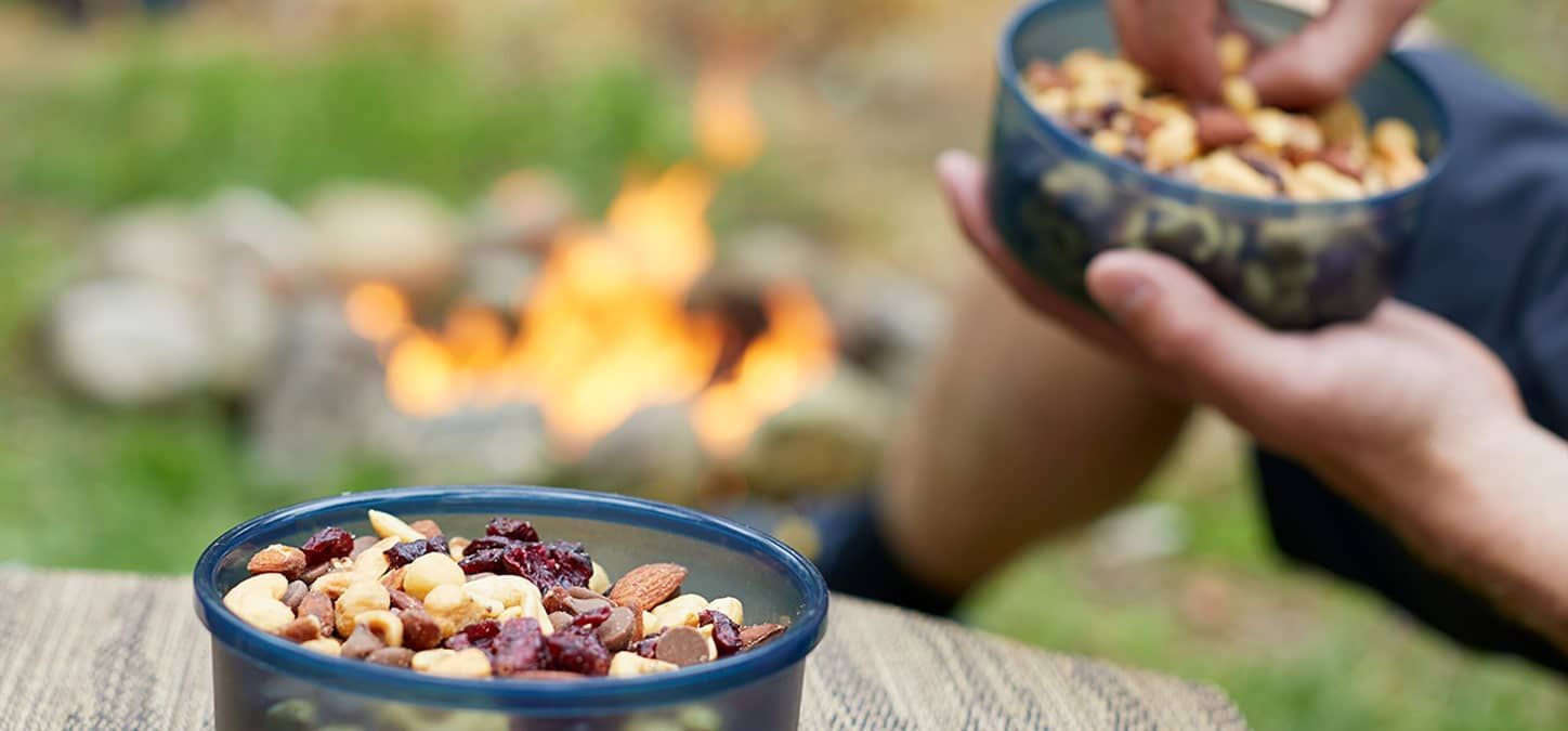 A person is eating nuts from a bowl in front of a fire.