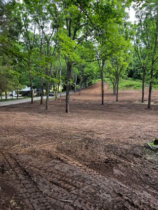 A tractor is driving down a dirt road in a park.