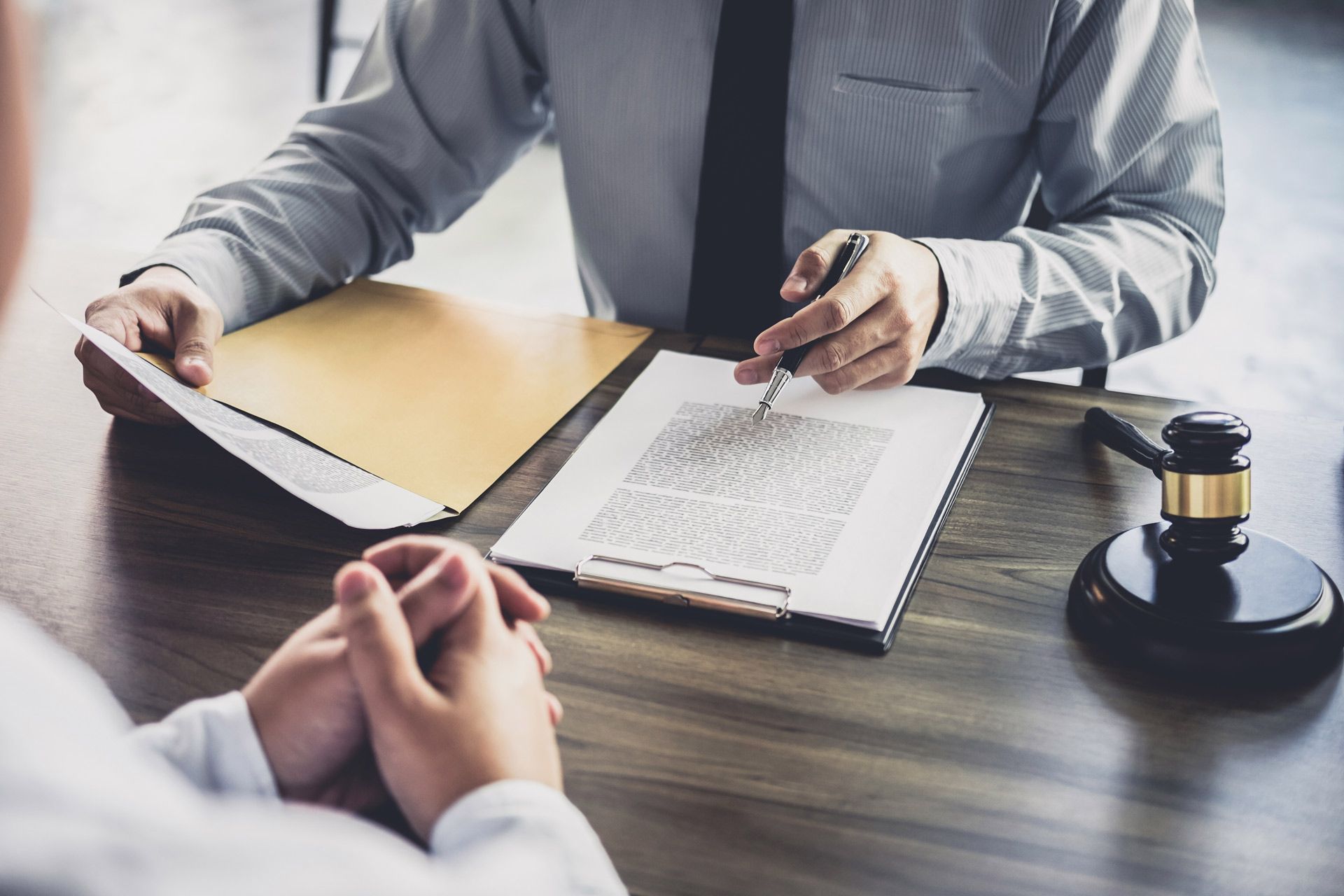 Lawyer discussing document with a client; gavel on the desk.