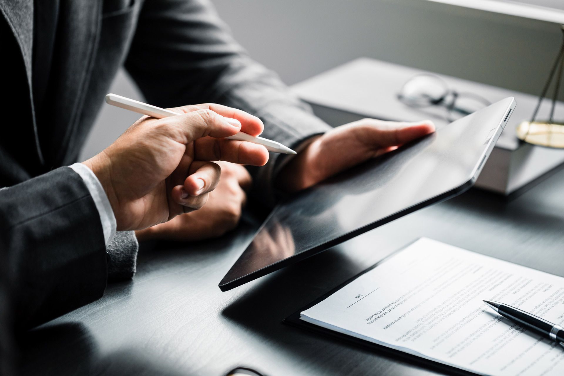 Person in suit using tablet, signing a document.