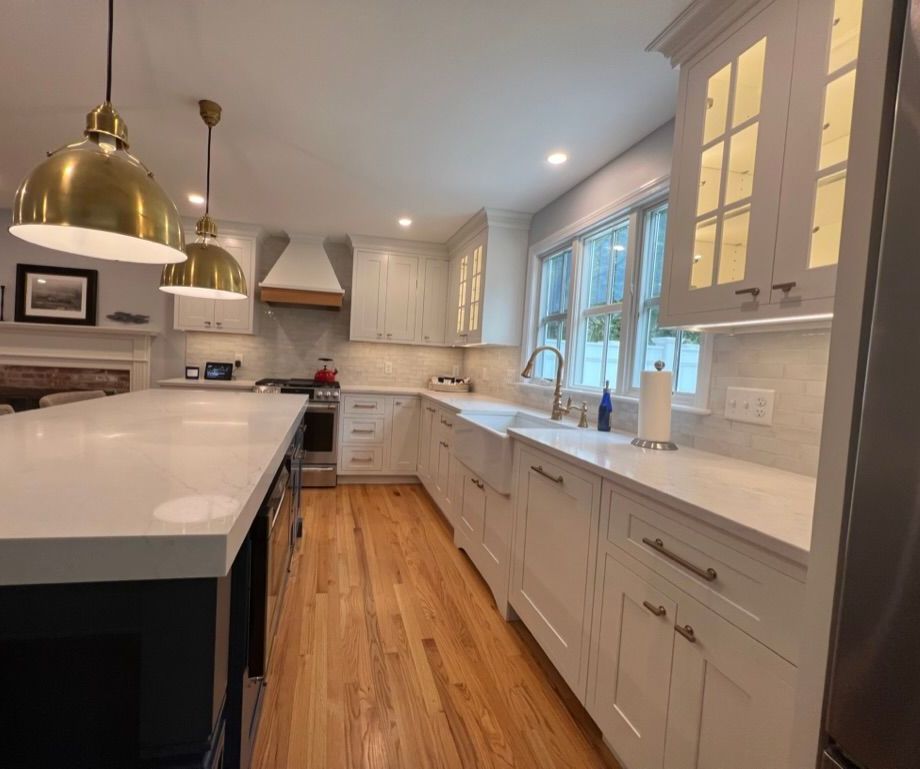 A kitchen with white cabinets and wooden floors