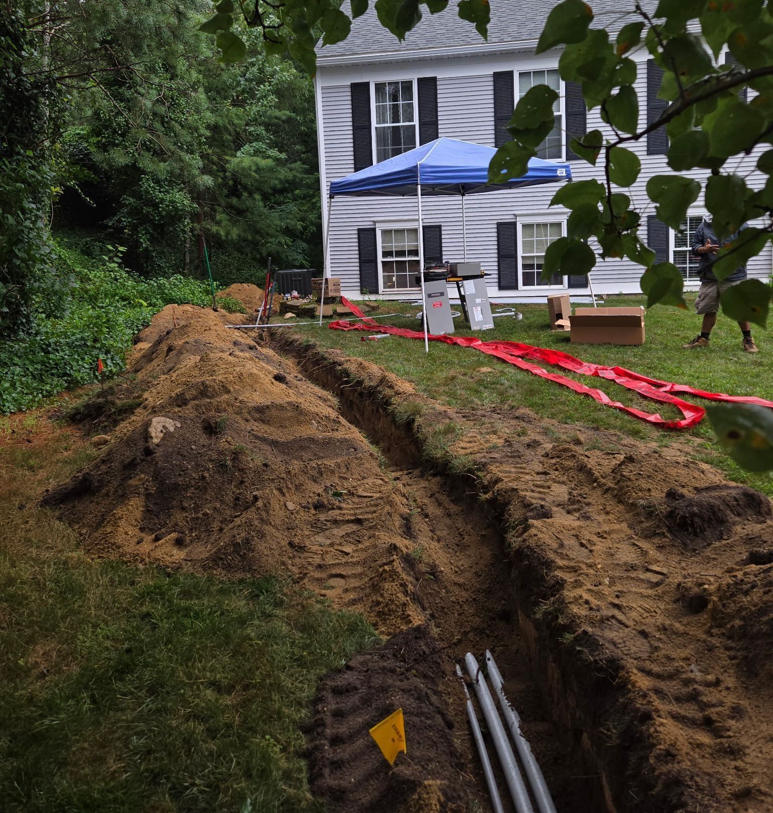 A white house with black shutters and a blue tent in the backyard