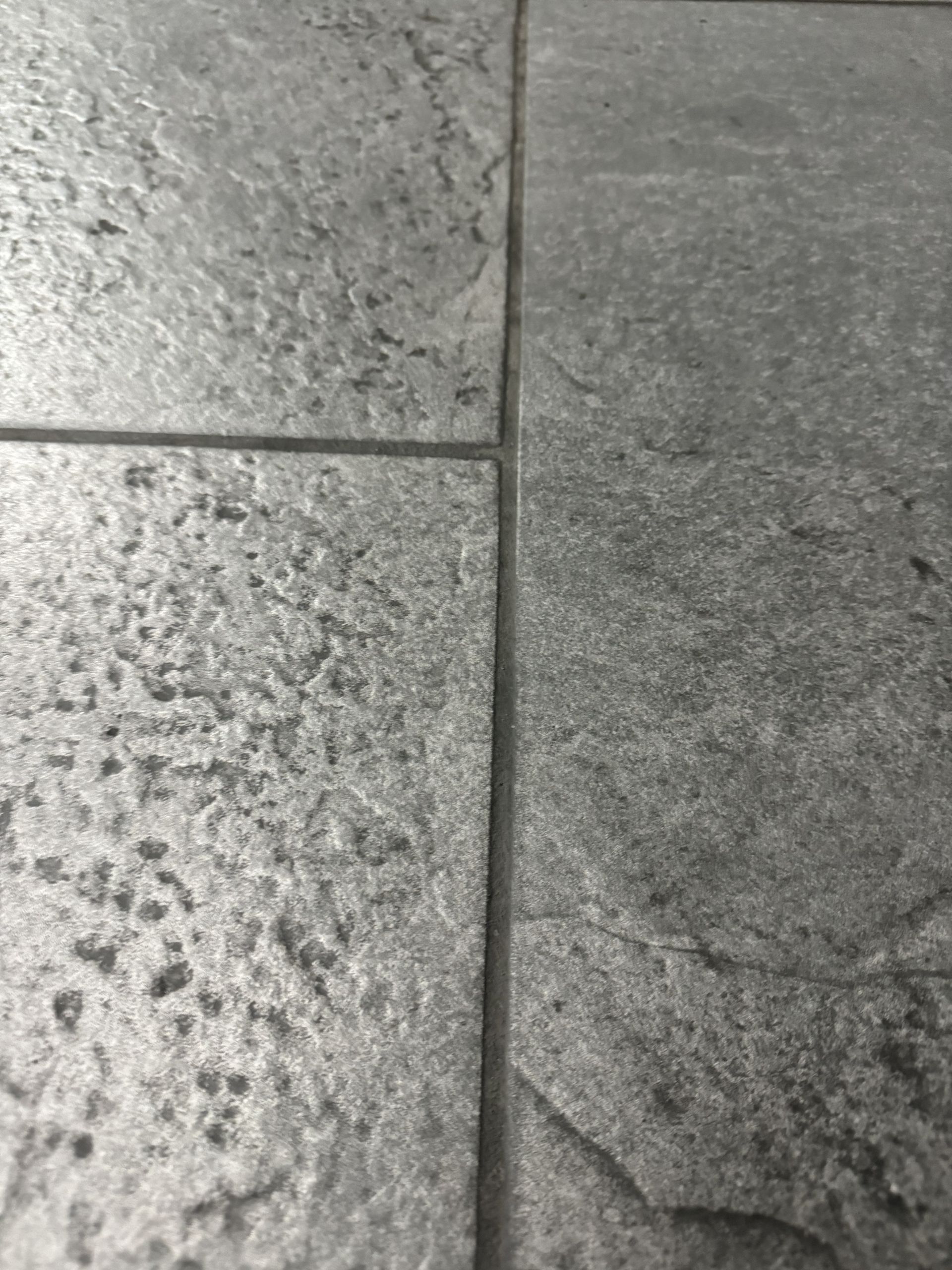 Close-up of gray, textured floor tiles with grout lines.