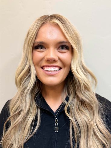 Woman with wavy blonde hair, smiling at the camera, wearing a black shirt.