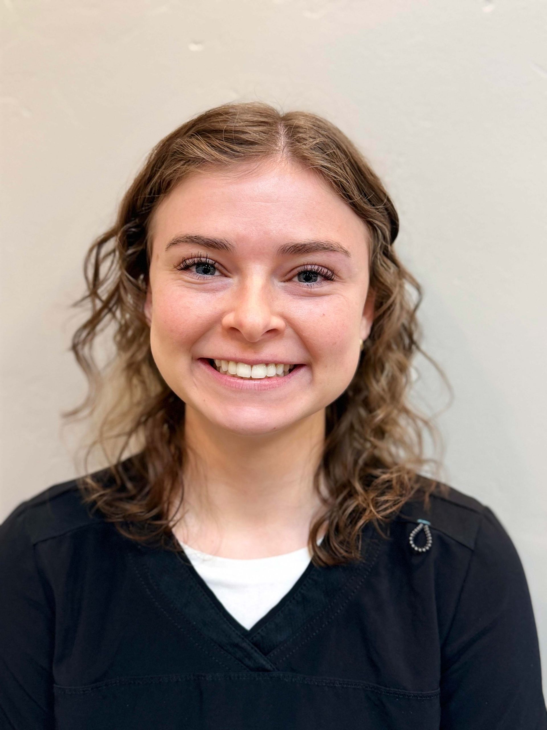 Smiling person in a black top against a light background.
