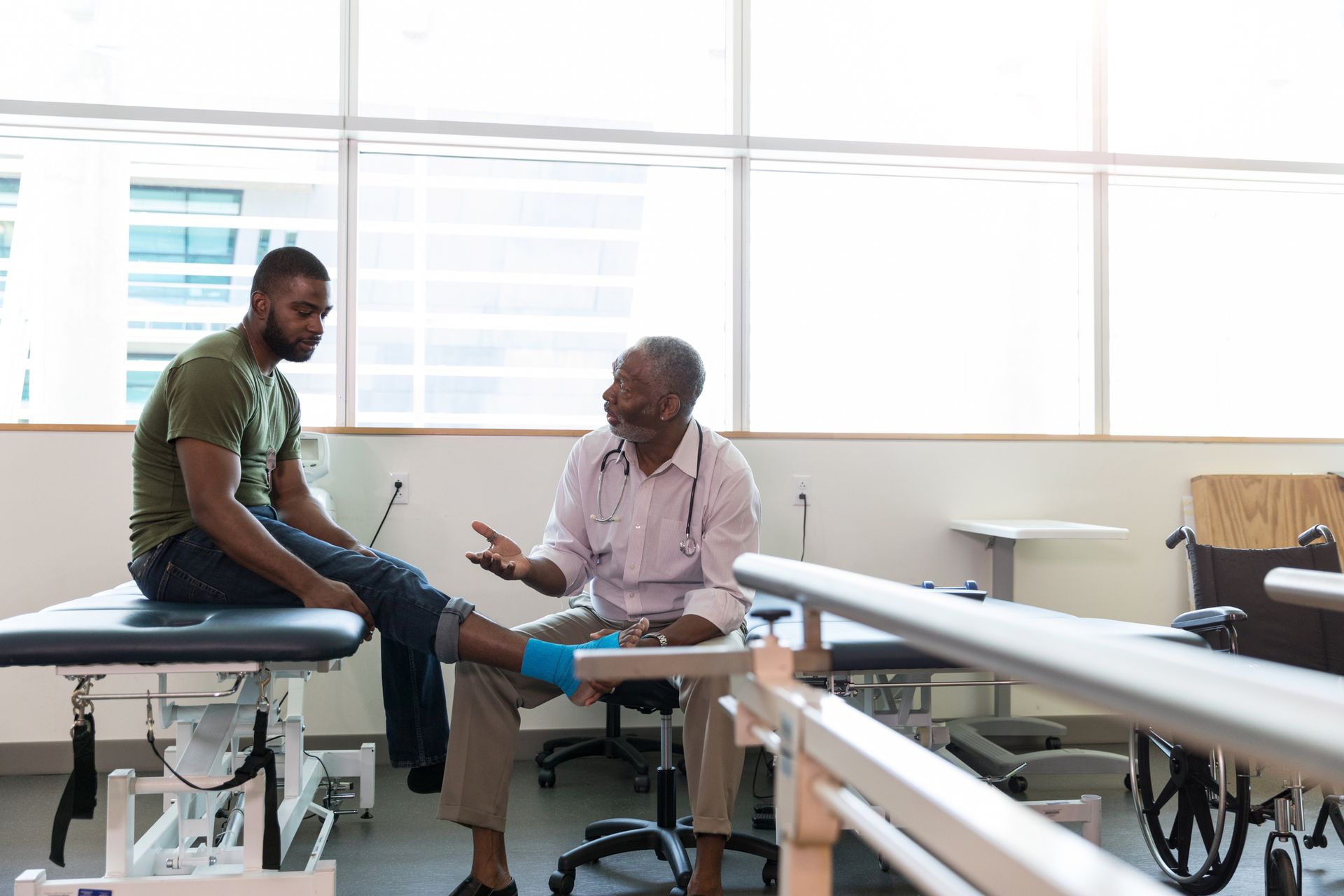 A man is sitting on a table talking to a doctor.