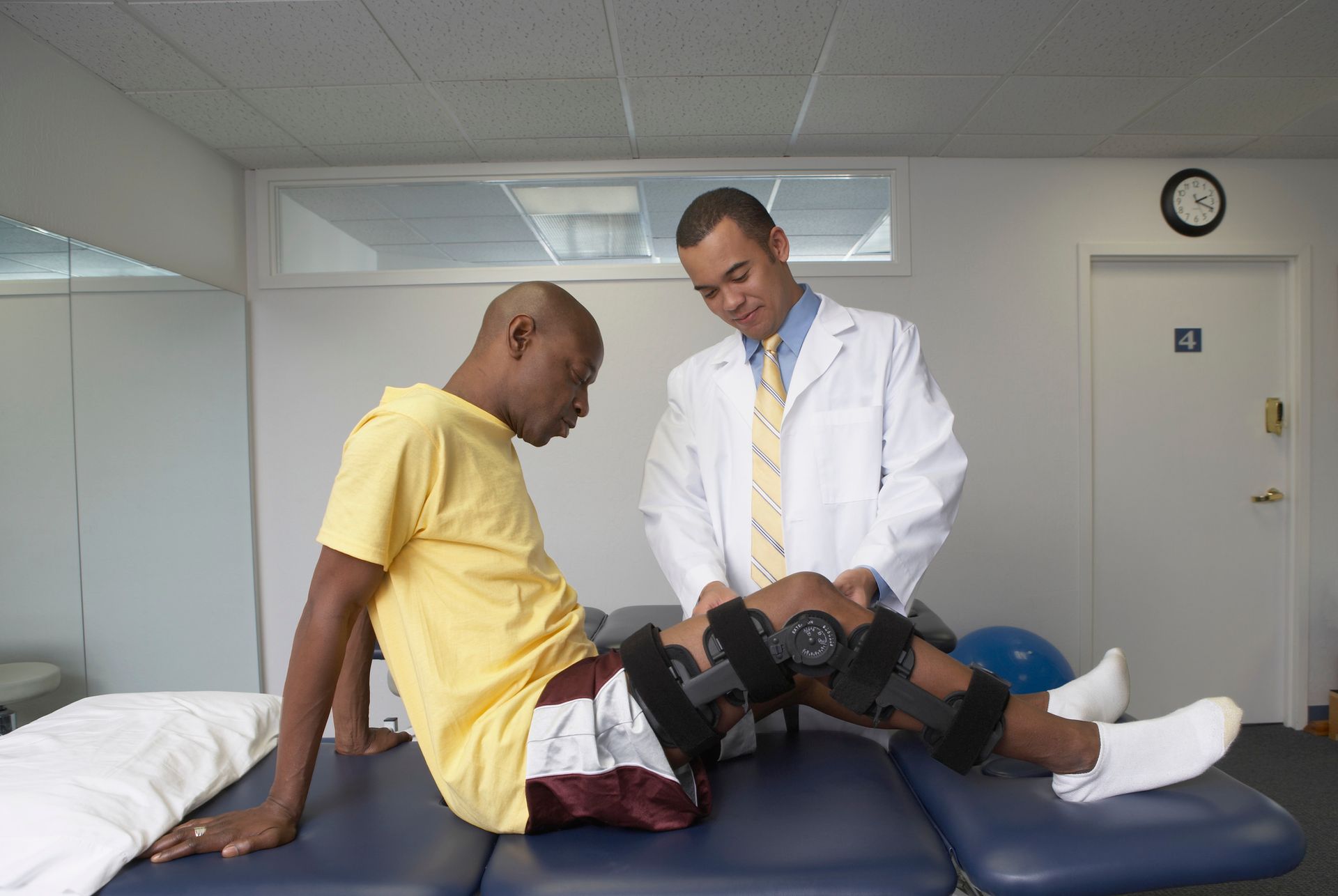 A man with a knee brace is being examined by a doctor