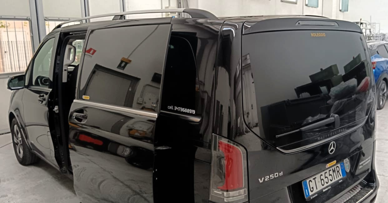 Un furgone Mercedes Classe V nero parcheggiato in un garage con lo sportello laterale aperto, che lascia intravedere l'interno.