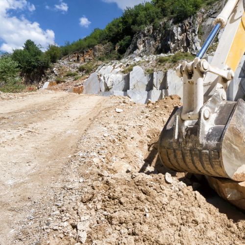 Una excavadora está moviendo tierra en un camino de tierra