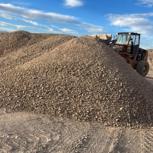 Una excavadora está moviendo un montón de tierra en el desierto.