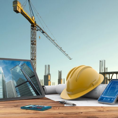 Un casco se encuentra sobre una mesa de madera junto a una computadora portátil.