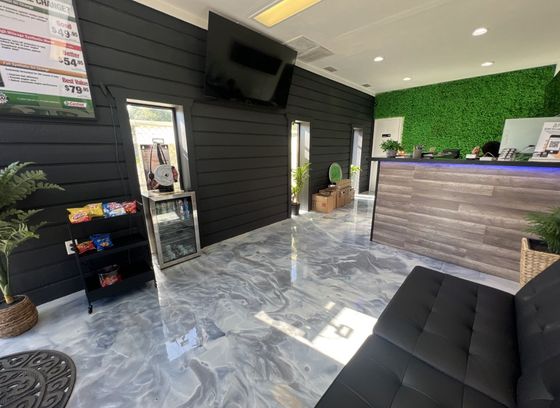 A waiting room with a couch , counter , and television.