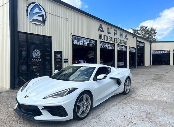 A white corvette is parked in front of a building.