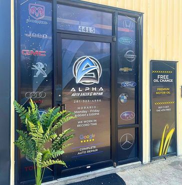 The front door of a car dealership with a plant in front of it.