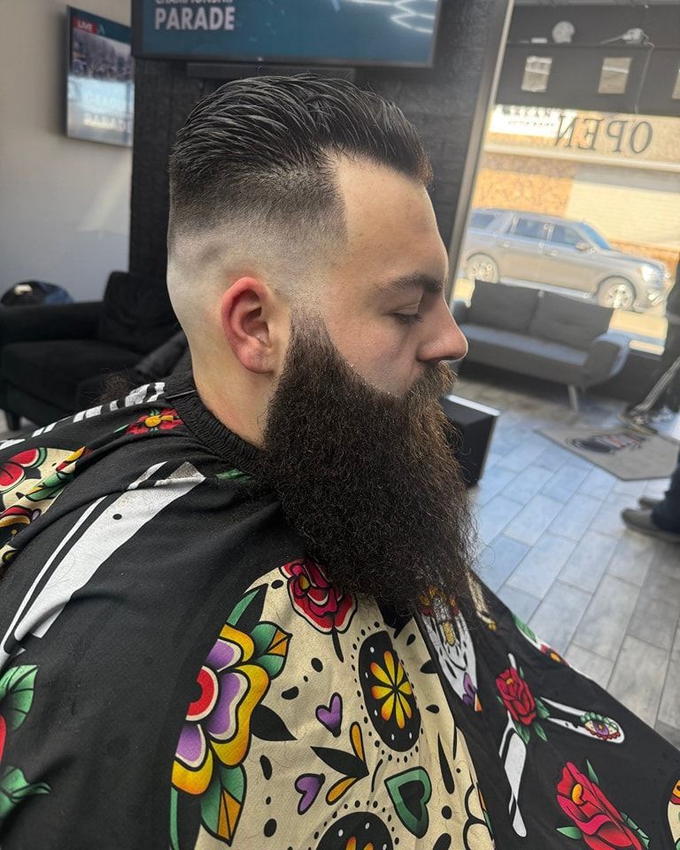 A man with a beard is getting his hair cut at a barber shop.