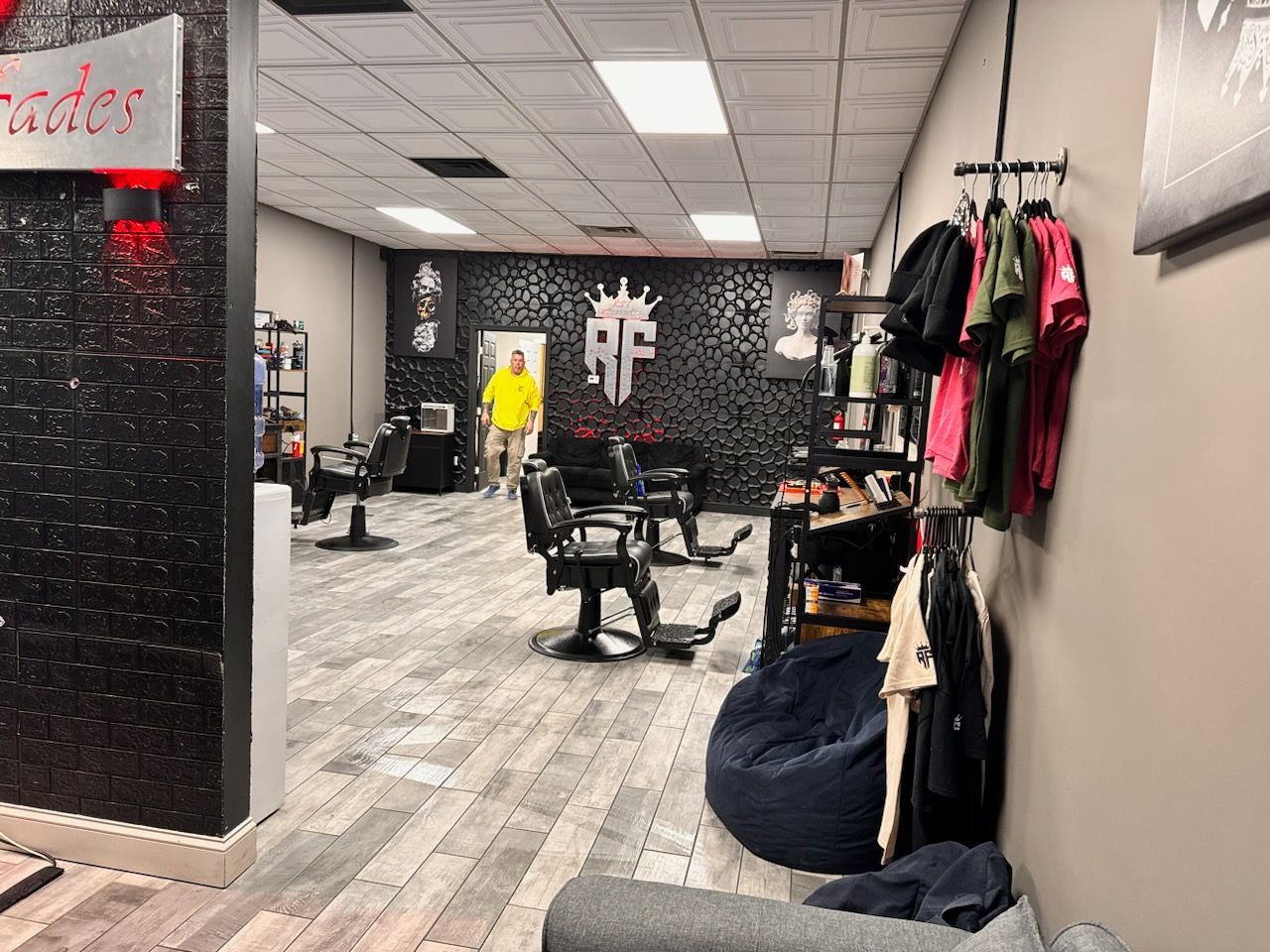 A man in a yellow shirt is standing in a barber shop.