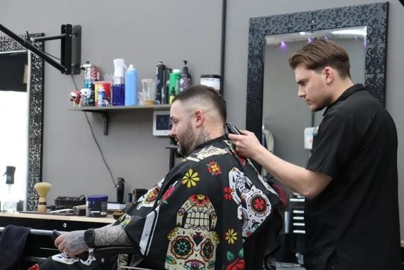 A man is getting his hair cut by a barber in a barber shop.