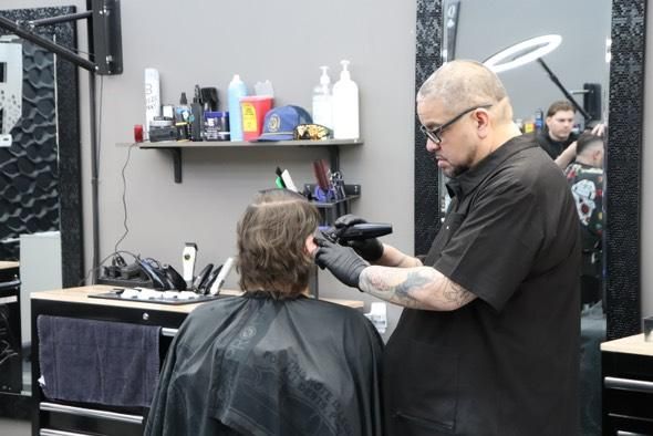 A man is getting his hair cut by a barber in a salon.