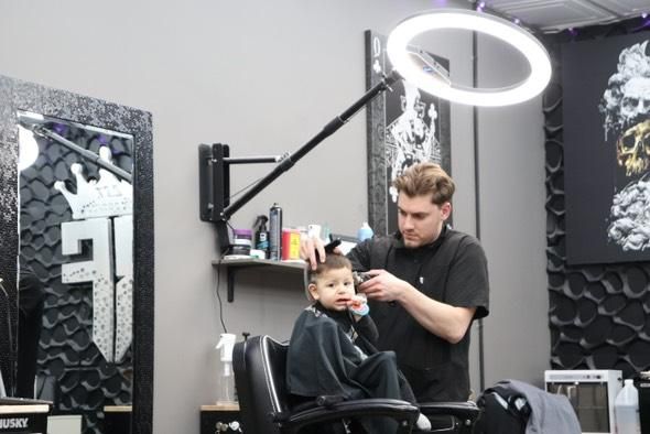 A man is cutting a little boy 's hair in a barber shop