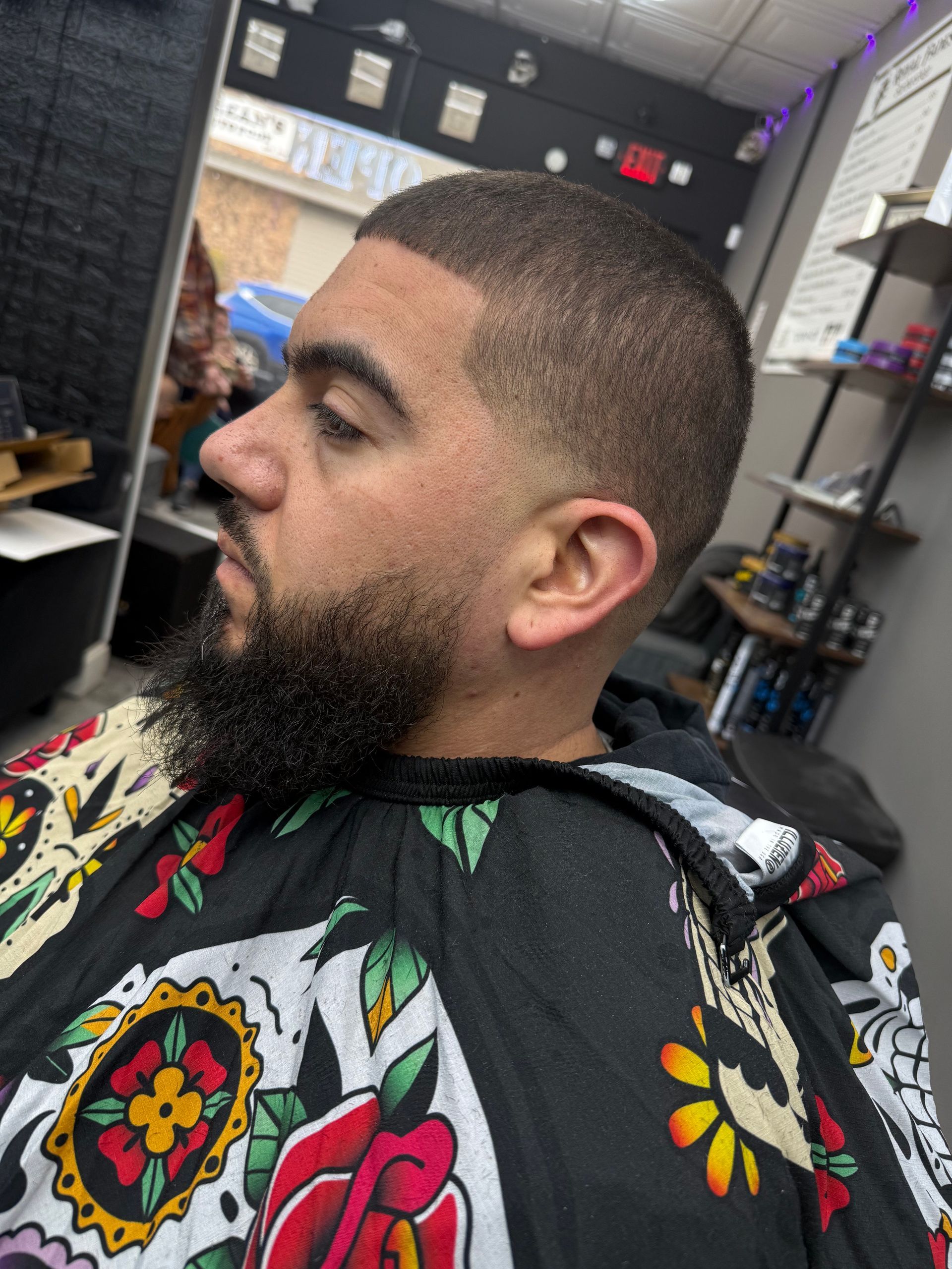 A man with a beard is getting his hair cut at a barber shop.