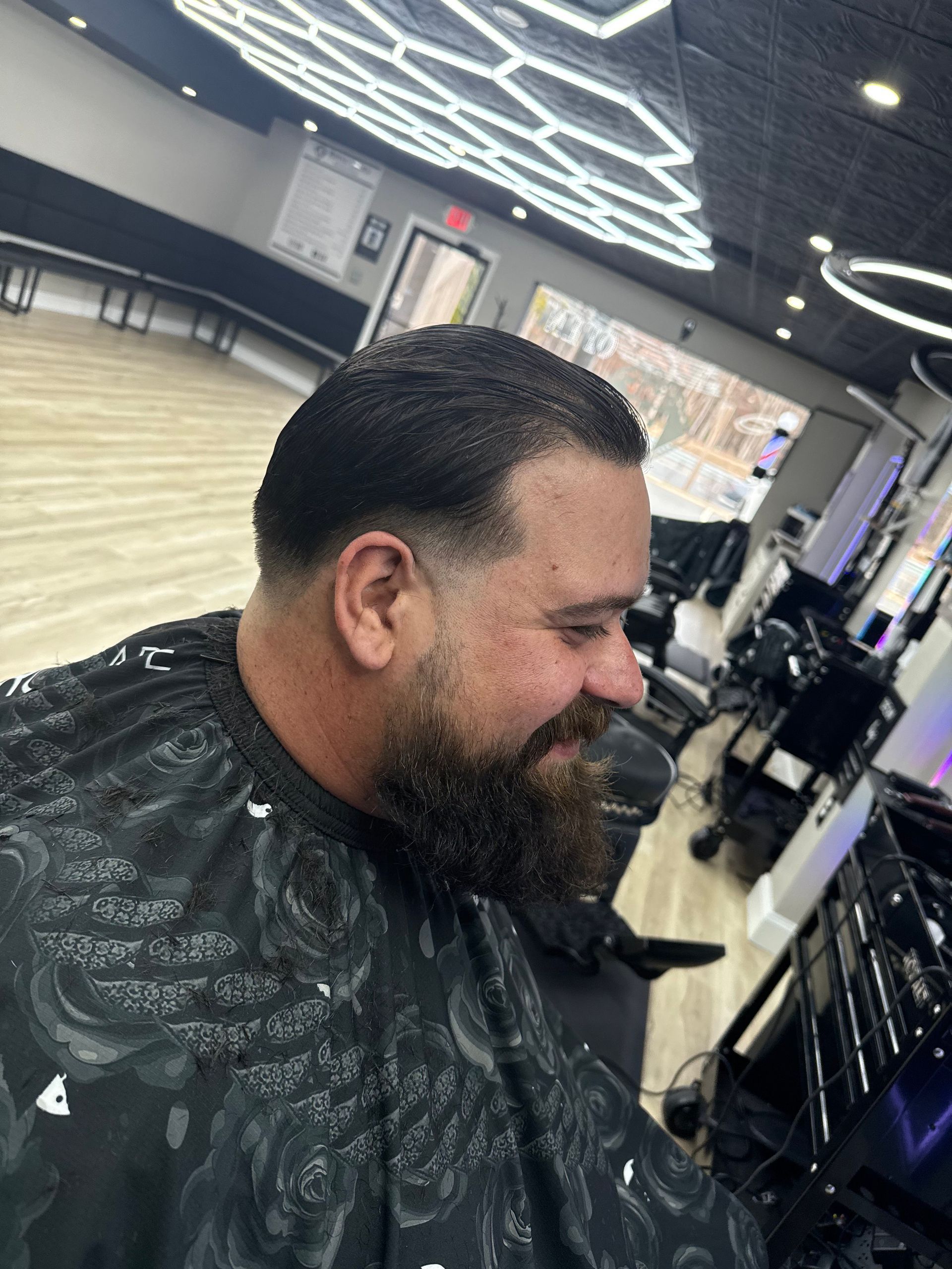 A man with a beard is getting his hair cut at a barber shop.