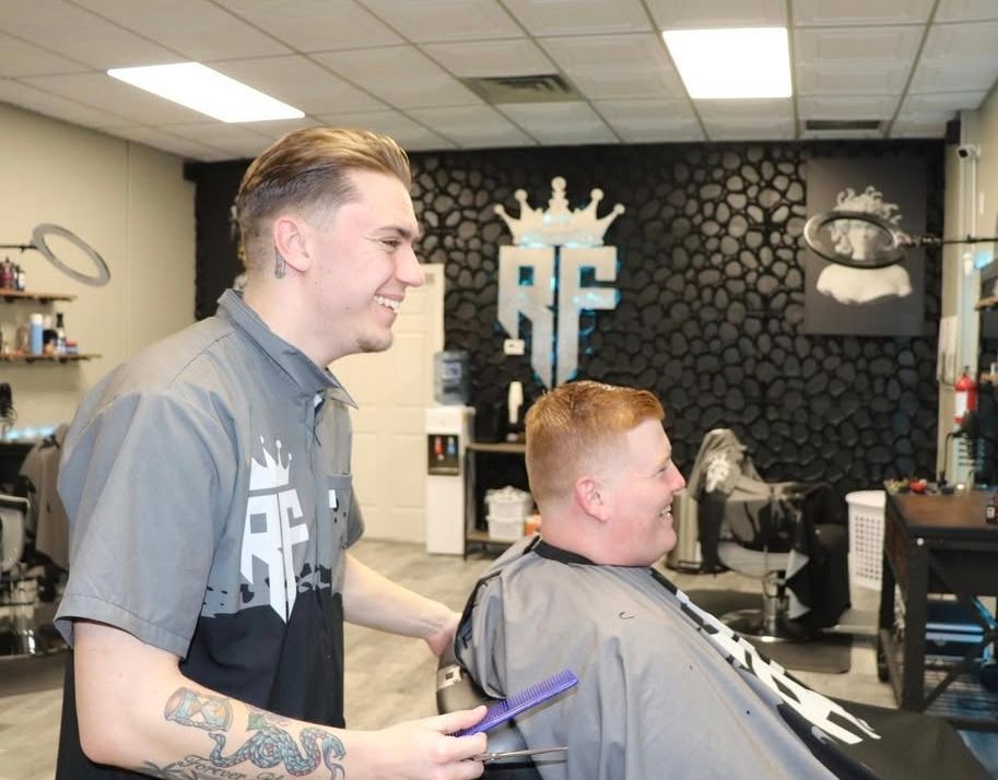 A man is getting his hair cut by a barber in a barber shop.