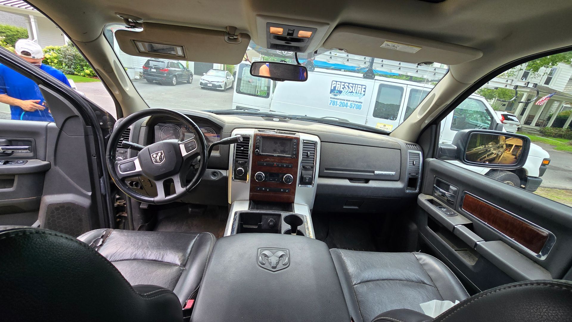 The interior of a dodge ram truck with a man standing in the background.