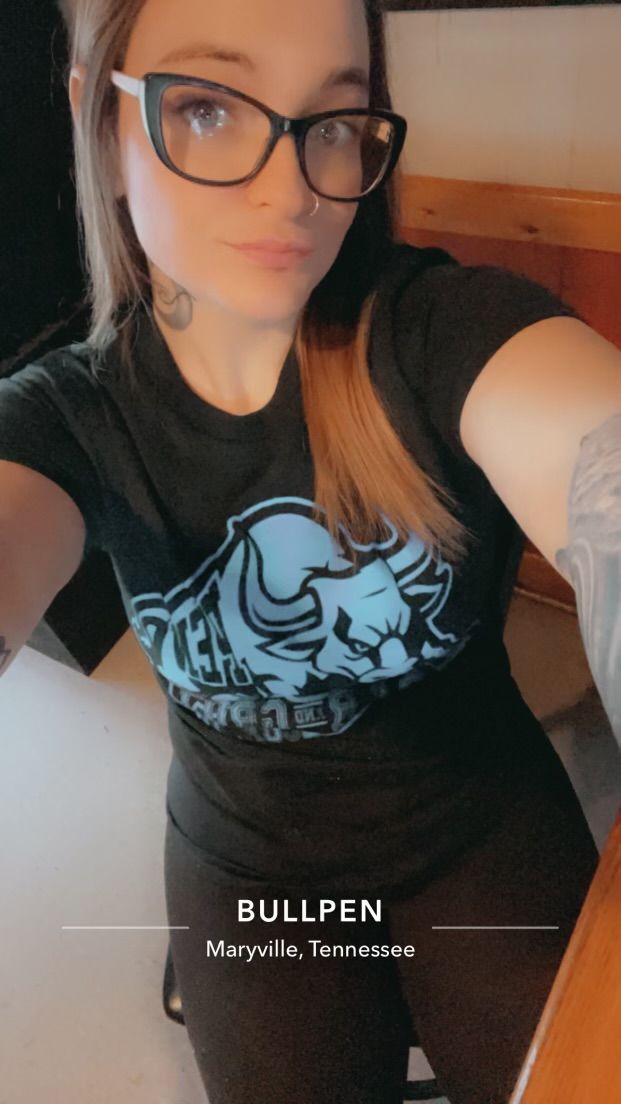 A woman wearing glasses and a black shirt is taking a selfie.